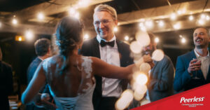 Bride and groom dancing at wedding reception, promoting Peerless dry cleaning services and wedding gown preservation for wedding season