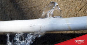 A close-up view of a cracked white pipe leaking water due to freezing and bursting.