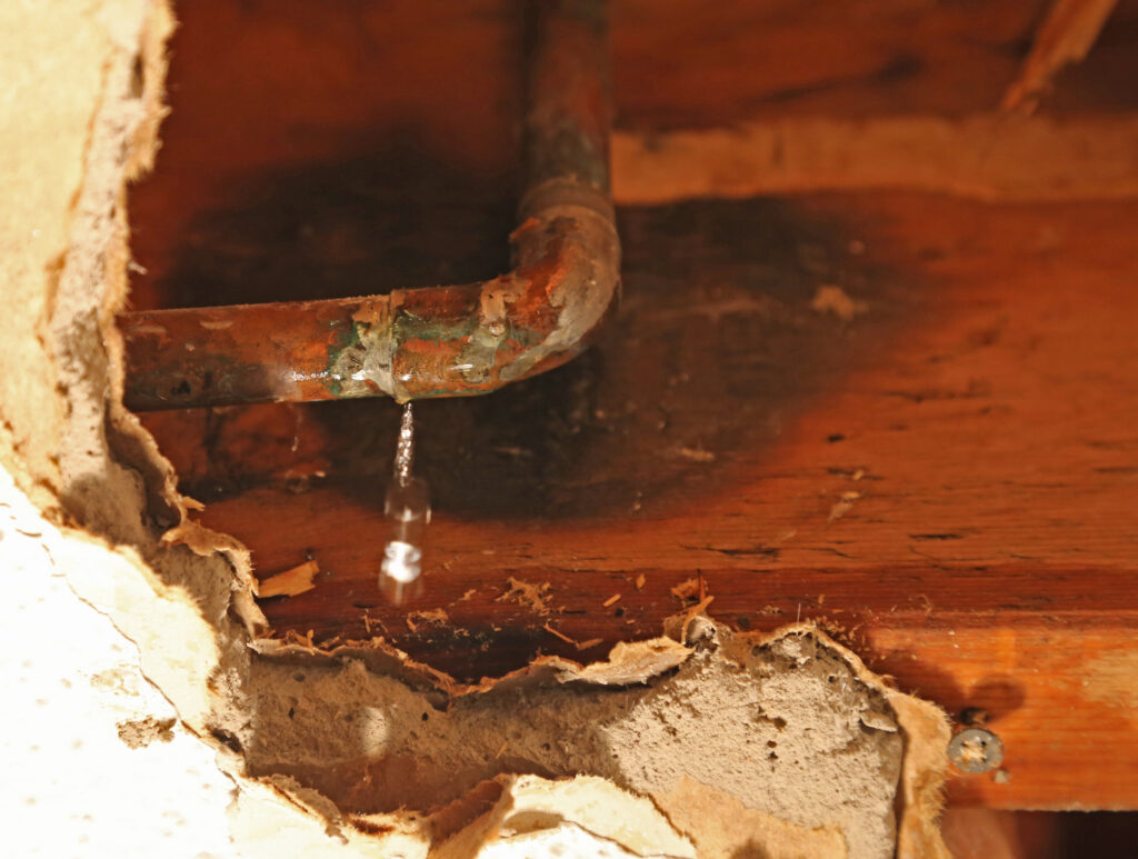 Leaking copper pipe inside a wall causing hidden water damage and moisture buildup behind drywall.