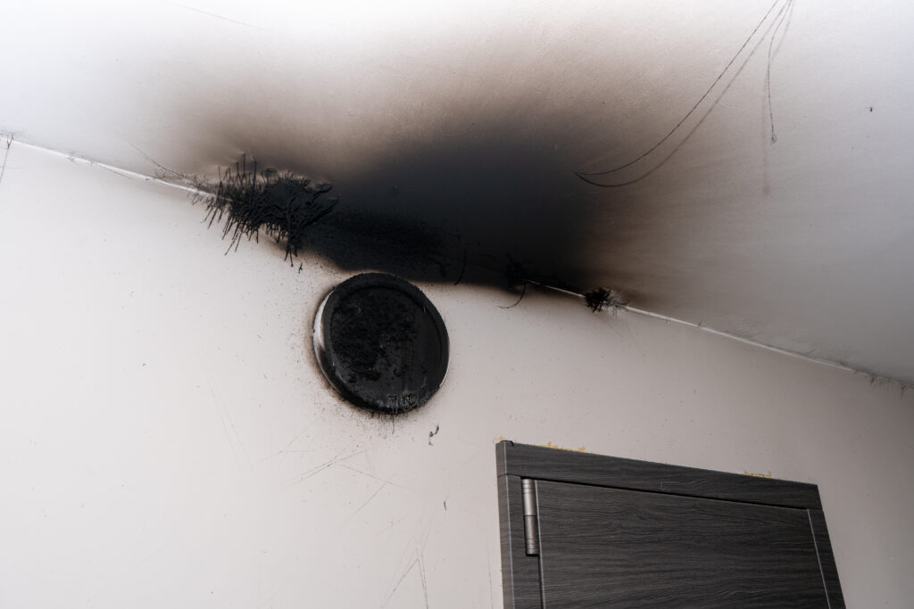 Heavy smoke and soot staining on a wall and ceiling after a residential fire.